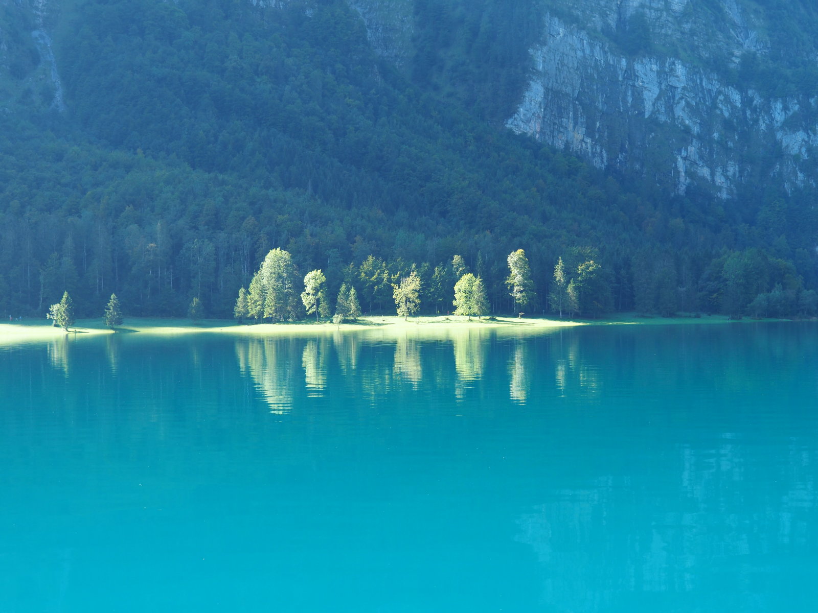 épp csak besüt a nap a tó partján, a magas hegyek takarják a napot
