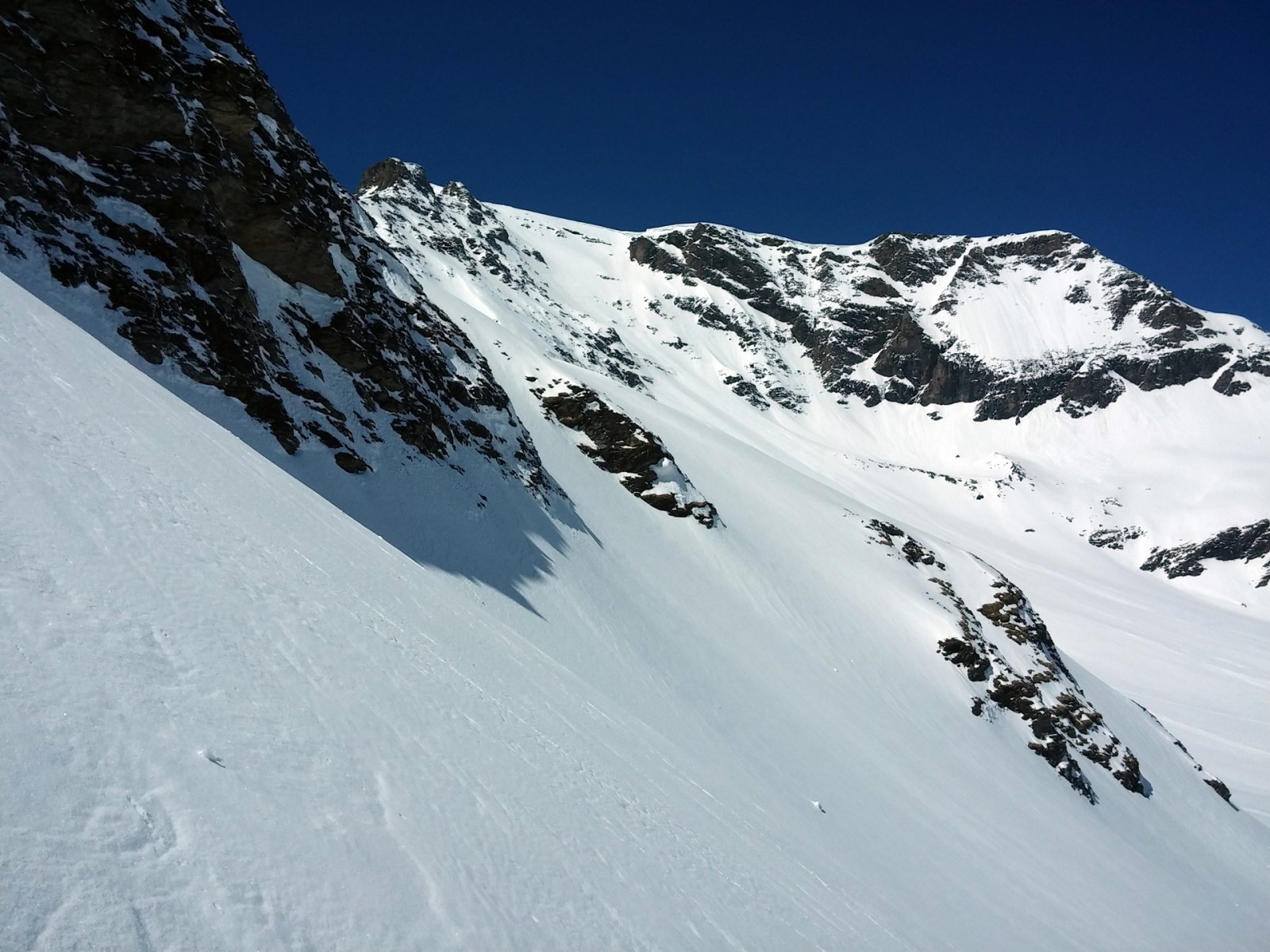 Tőlünk balra a lejárat, ahonnan a társakat vártuk. A hátsó napsütötte hegyoldalon spontán lavinák gördültek le.