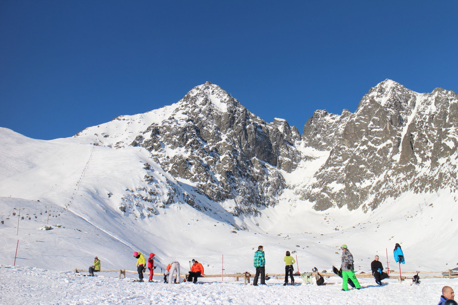 Síelés verőfényes napsütésben: balról a Lomnici-nyereg pályája, középen pedig a Lomnici-csúcs látható