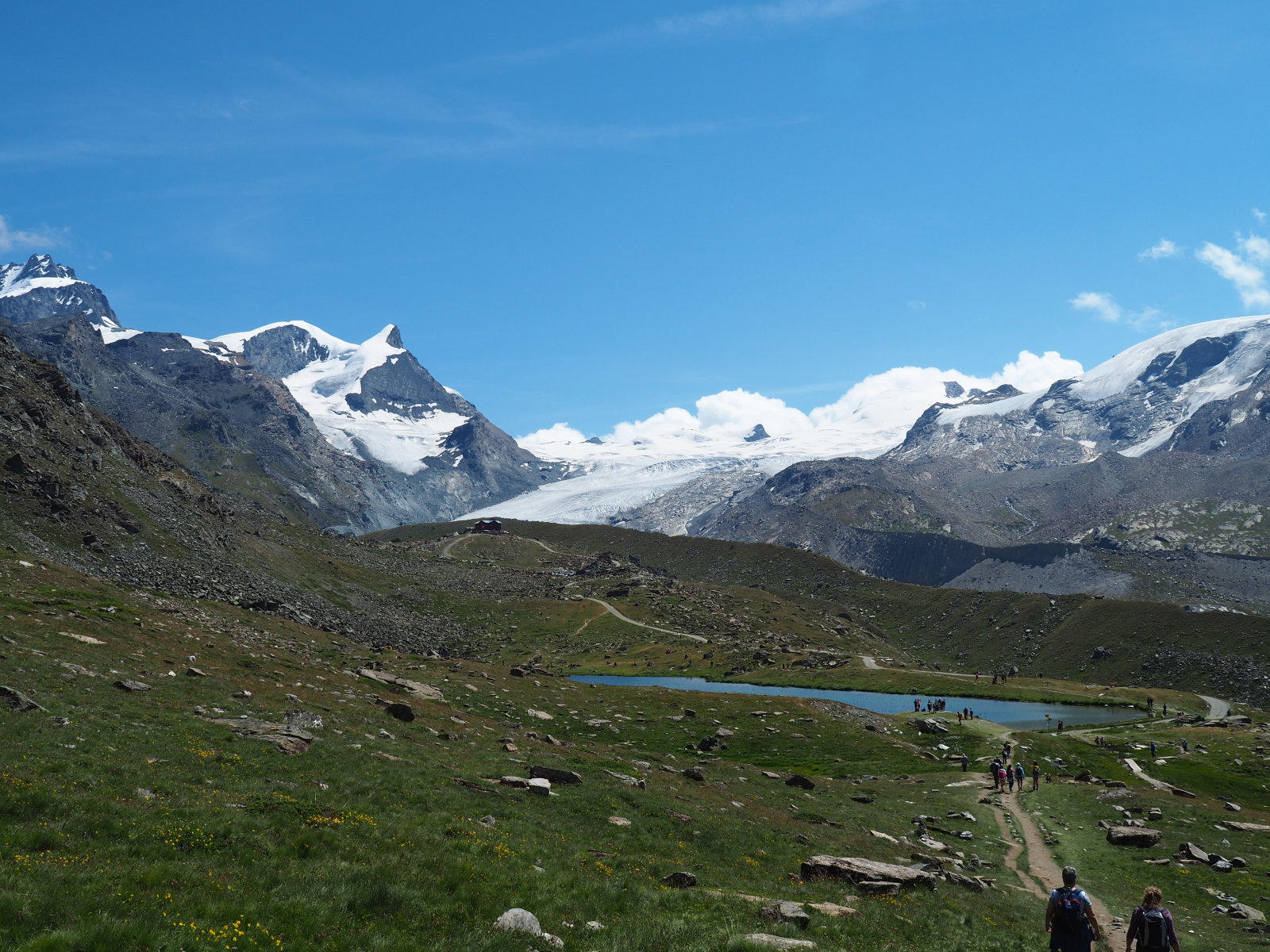 Az első tó Stellisee, a havas hegyek mögött a völgyben Saas-Fee található