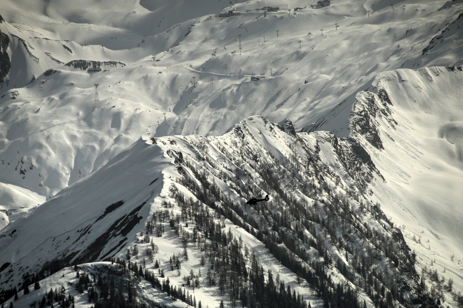 Repülő suhan a hegyek felett, a háttérben a kapruni sípályák alja