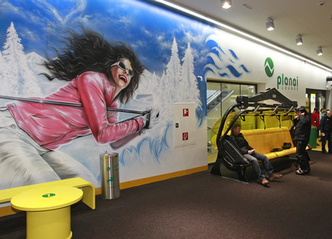 A Planai új ingyenes mélygarázsa tele van ötletekkel. A falakat a Redbull designerének festményei díszítik, hogy ne nyomasszon senkit a parkolóház-depresszió. Vége a kocsiban átöltözésnek! A síelők kényelmes ülőhelyeken vehetik fel és le a síbakancsot, ülőkék, hókefék, tágas, tisztálkodó helyiségek, öltözők állnak rendelkezésre. A mozgólépcső pedig közvetlenül a Planai bejáratához visz fel - teljes a kényelem!